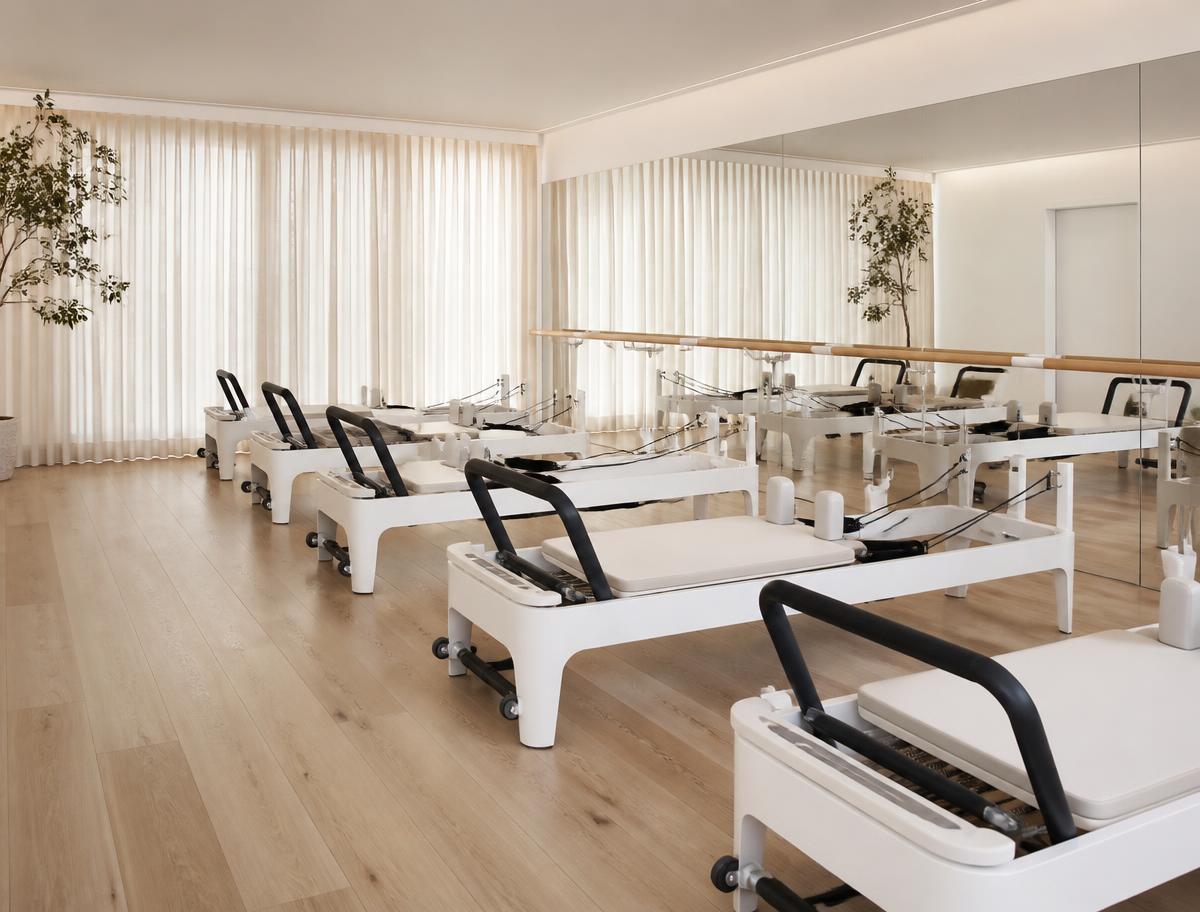 White reformer machines arranged for a small group class in a bright studio